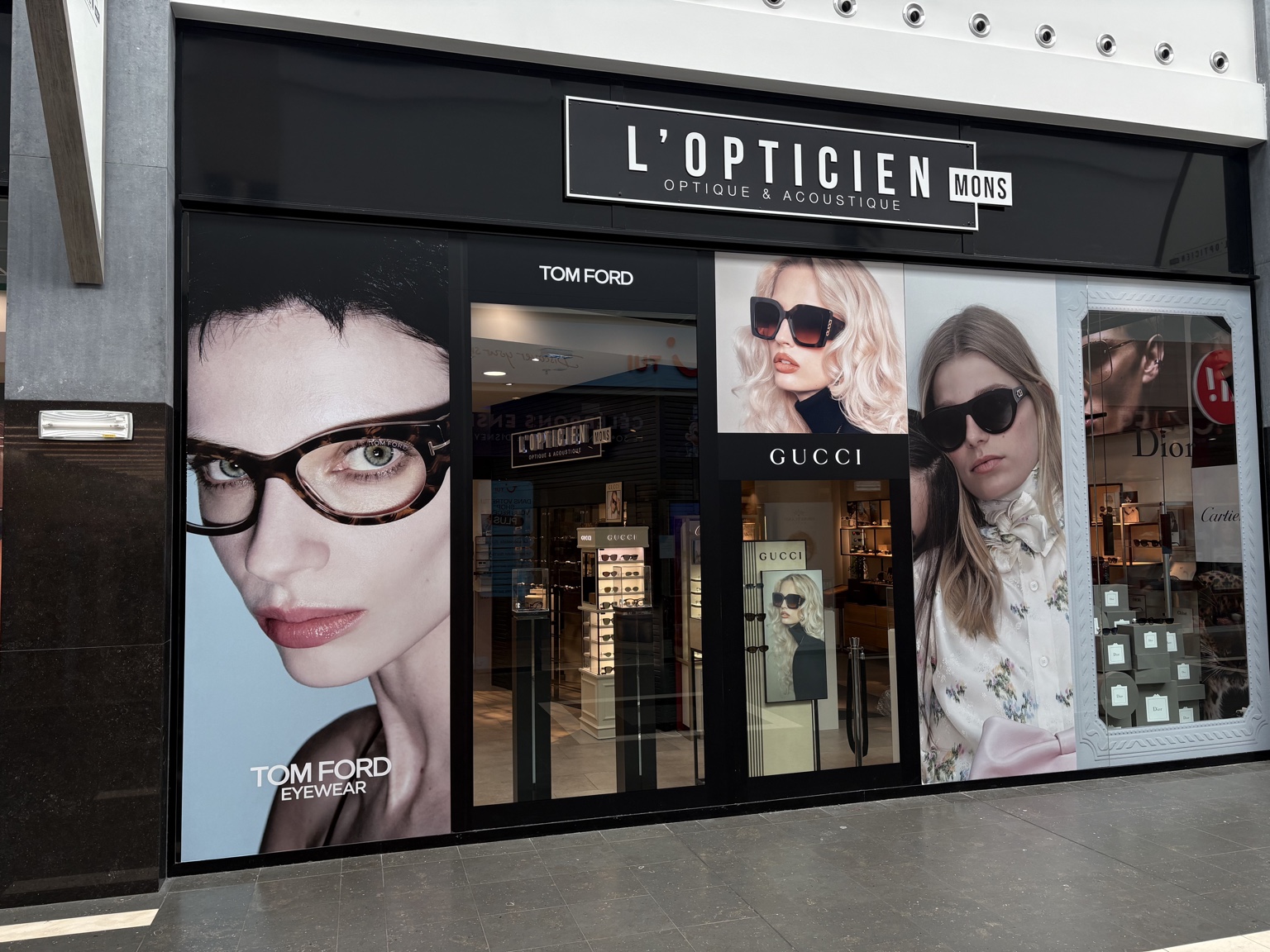 Vue complète de la façade L’Opticien Mons avec visuels Tom Ford, Gucci et Dior